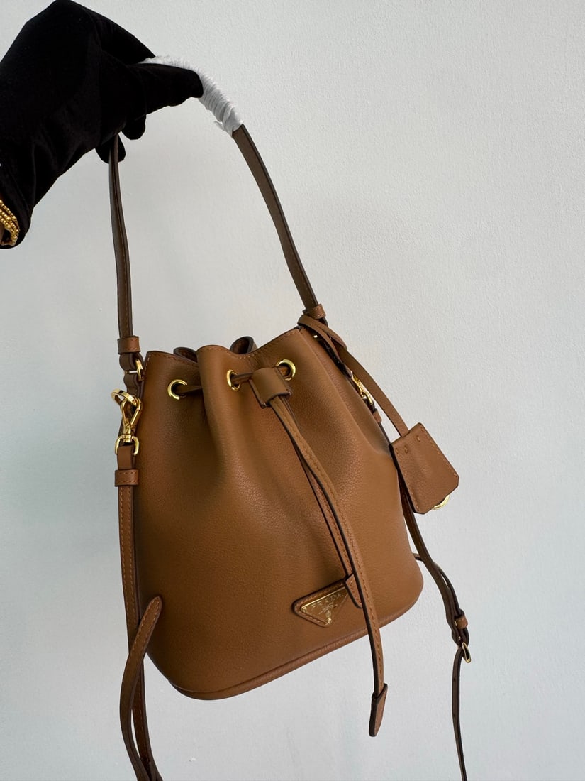 PRADA bucket bag: This stylish mini bucket bag features a soft bucket shape, adorned with delicate gold-plated hardware and the iconic triangular logo. Made of leather, it includes an adjustable shoulder strap for adde