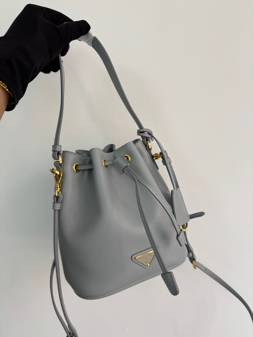 PRADA bucket bag: This stylish mini bucket bag features a soft bucket shape, adorned with delicate gold-plated hardware and the iconic triangular logo. Made of leather, it includes an adjustable shoulder strap for adde