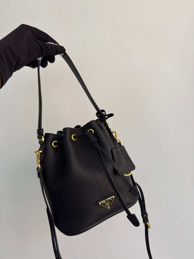 PRADA bucket bag: This stylish mini bucket bag features a soft bucket shape, adorned with delicate gold-plated hardware and the iconic triangular logo. Made of leather, it includes an adjustable shoulder strap for adde