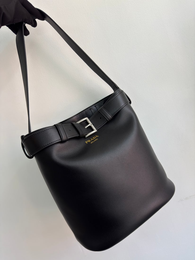 PRADA bucket bag: This stylish bucket bag offers a fresh take on the classic bucket silhouette. Made with imported calfskin and imported lambskin lining, it features a leather strap with a detachable classic buckle for
