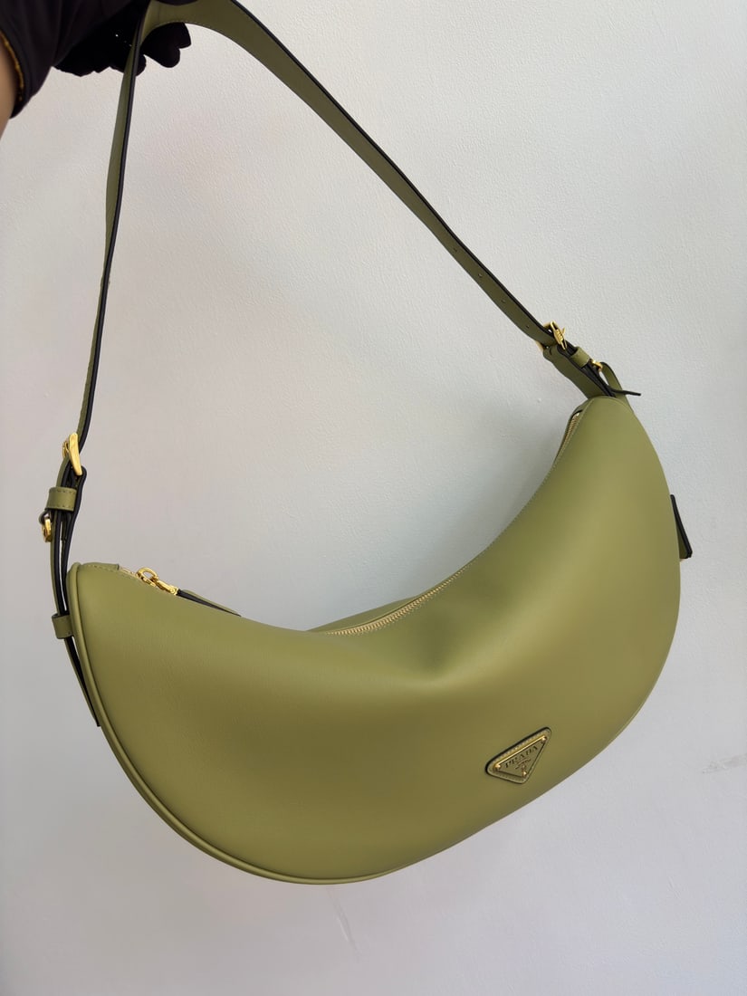 PRADA underarm bag: This leather underarm bag features a soft and lightweight design, offering a fresh interpretation of the classic crescent shape. Its elegant curves accentuate its oversized silhouette, creating a spac