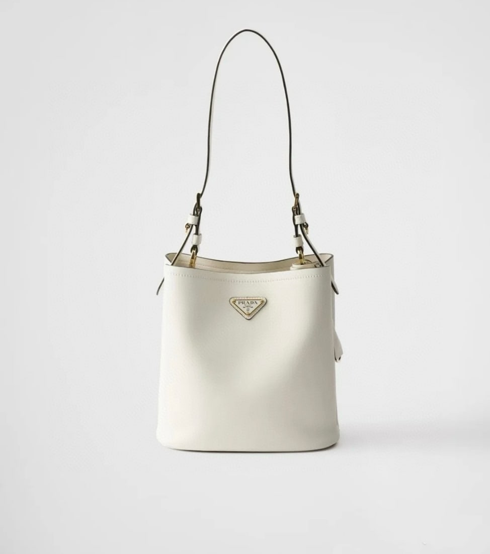 PRADA bucket bag: This bucket bag, made of leather, boasts soft lines and exquisite design, highlighting classic style and handcrafted details. Practical and versatile, it features an enamel triangular metal logo for a