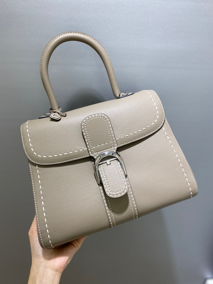 Delvaux brillant: Delvaux brillant, a Belgian royal warrant holder with a creamy grey exterior, exudes understated luxury with semi-hand-stitched waxed thread. Comes with an adjustable shoulder strap and a mirror. Lamb