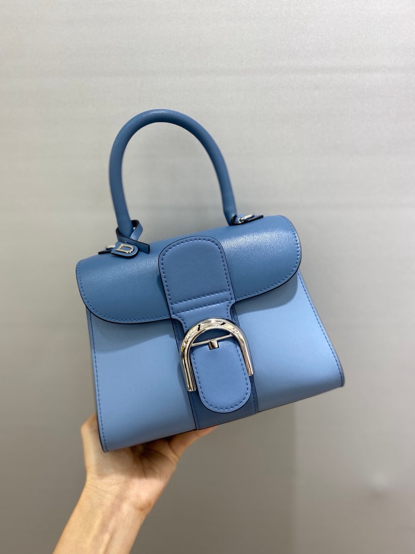 Delvaux brillant: This blue tri-tone Delvaux brillant, a Belgian royal warrant holder, features a double-ring brillant box leather upper with lambskin lining, an adjustable long shoulder strap, a mirror, and a small ch