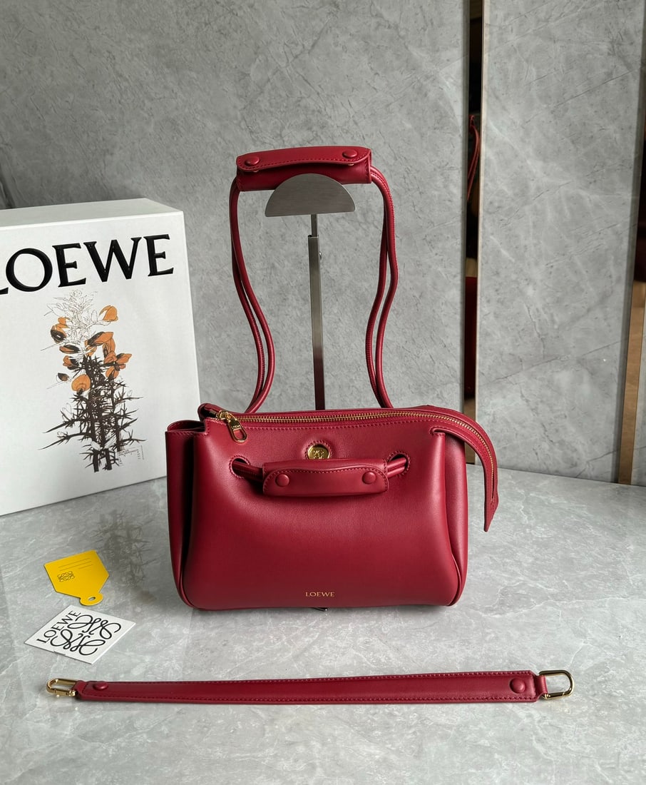 LOEWE: The LOEWE Small Madrid bag boasts a sculpted, structured trapezoidal shape with a gusseted design, adjustable handles, and a Pebble magnetic closure. Made from supple cowhide leather, it features a pr