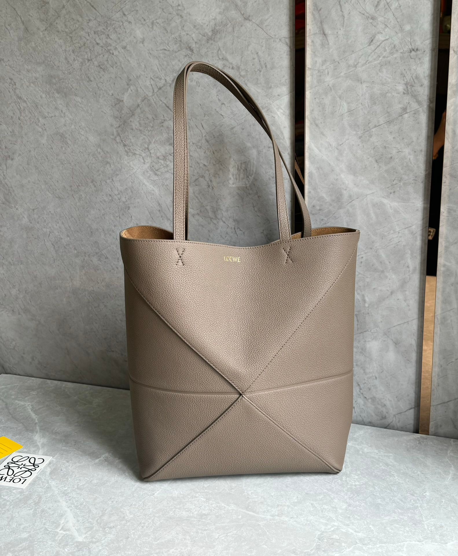 LOEWE: The LOEWE Puzzle Fold Tote is crafted from pebbled Nappa calfskin. Inspired by origami, the Puzzle Fold Tote boasts clean lines and an understated elegance. It's incredibly soft, spacious, and its mos