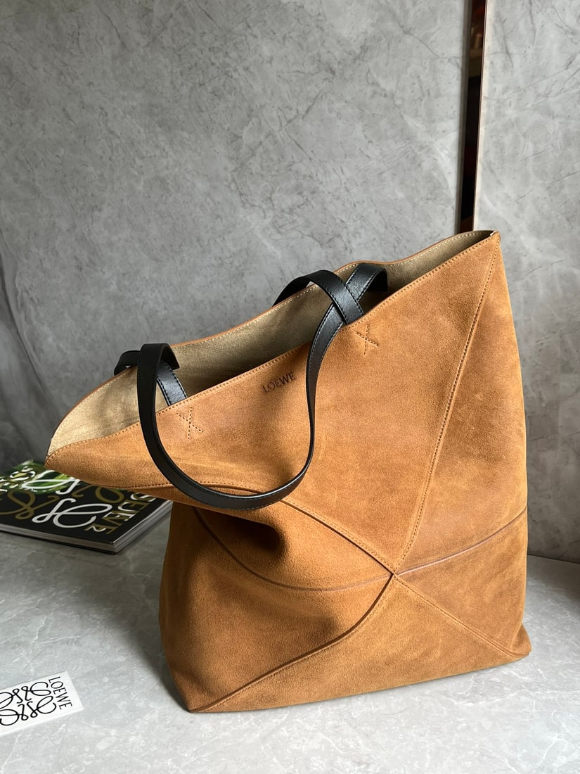 LOEWE: The large embossed suede Puzzle Fold handbag draws inspiration from the geometric lines of the brand's classic handbag collection, reinterpreted with geometrically architectural panels, and can be ful