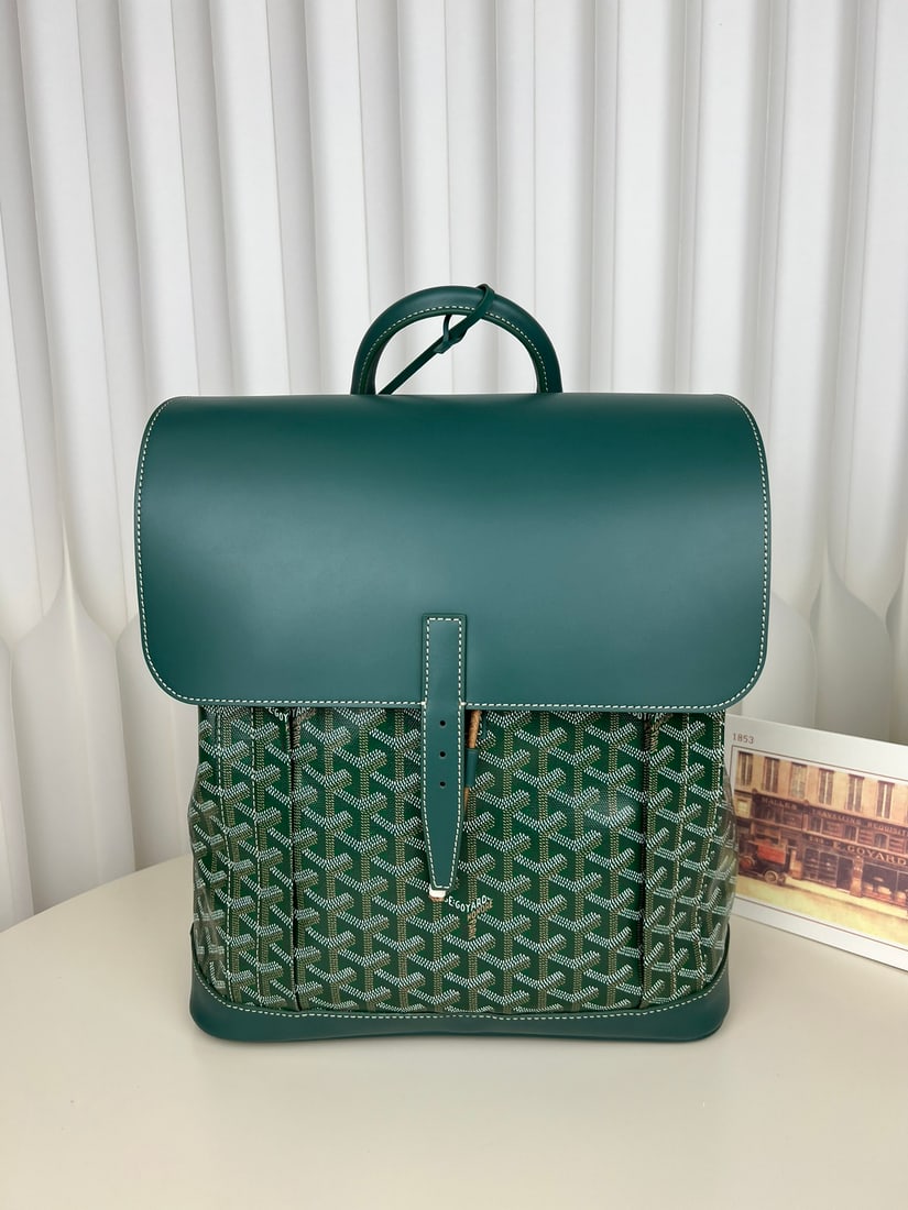Goyard Alpin MM: The Goyard Alpin MM men's flap backpack is a design by Goyard specifically for urban adventurers. A reinvention of the brand's renowned Steamer bag, it was a loyal companion to 20th-century travelers.
