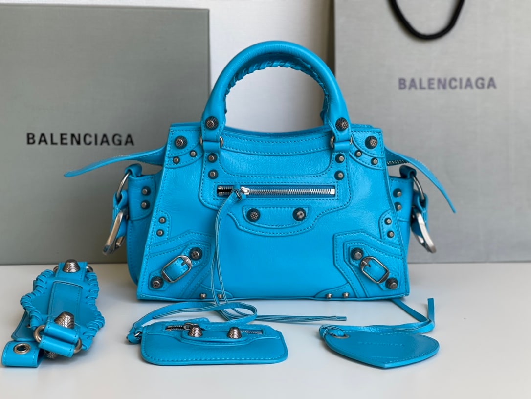 Balenciaga Neo Cagole Motorcycle Bag: The Balenciaga Neo Cagole motorcycle bag in waxed blue comes with a heart-shaped mirror. Beneath its cool exterior lies a sweet heart; carrying it instantly elevates your style. A must-have for the ch