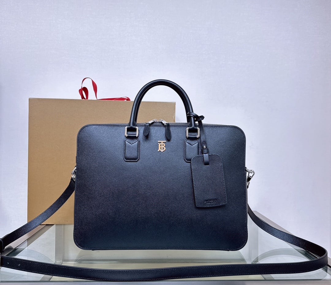 Burberry briefcase: This Burberry stand-up briefcase is crafted in Italy from grained calfskin. Its slim design features a luggage tag and a palladium-plated TB logo. It has a rolled leather top handle and a detachable, 