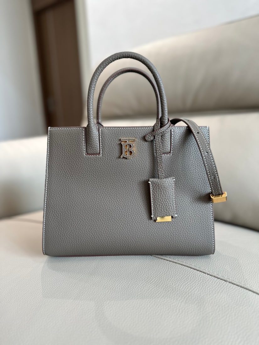 Burberry: This structured Burberry tote bag is crafted from Italian-tanned grained leather and features a striking Thomas Burberry logo with a glossy finish. The sophisticated design includes multiple pockets a