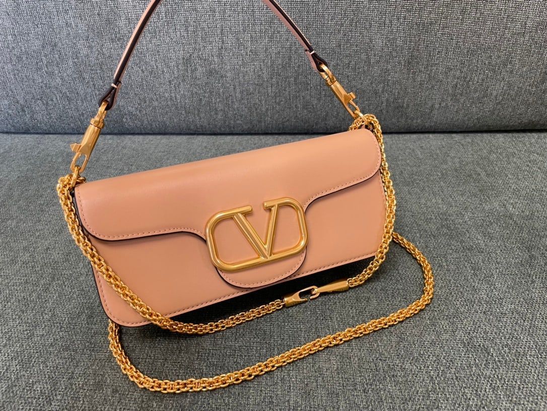 Valentino: Apricot Valentino calfskin handbag with gold hardware and a metal V-logo signacar trim. Features a detachable handle and sliding chain for shoulder, crossbody, or hand carrying. Vintage brass finish h