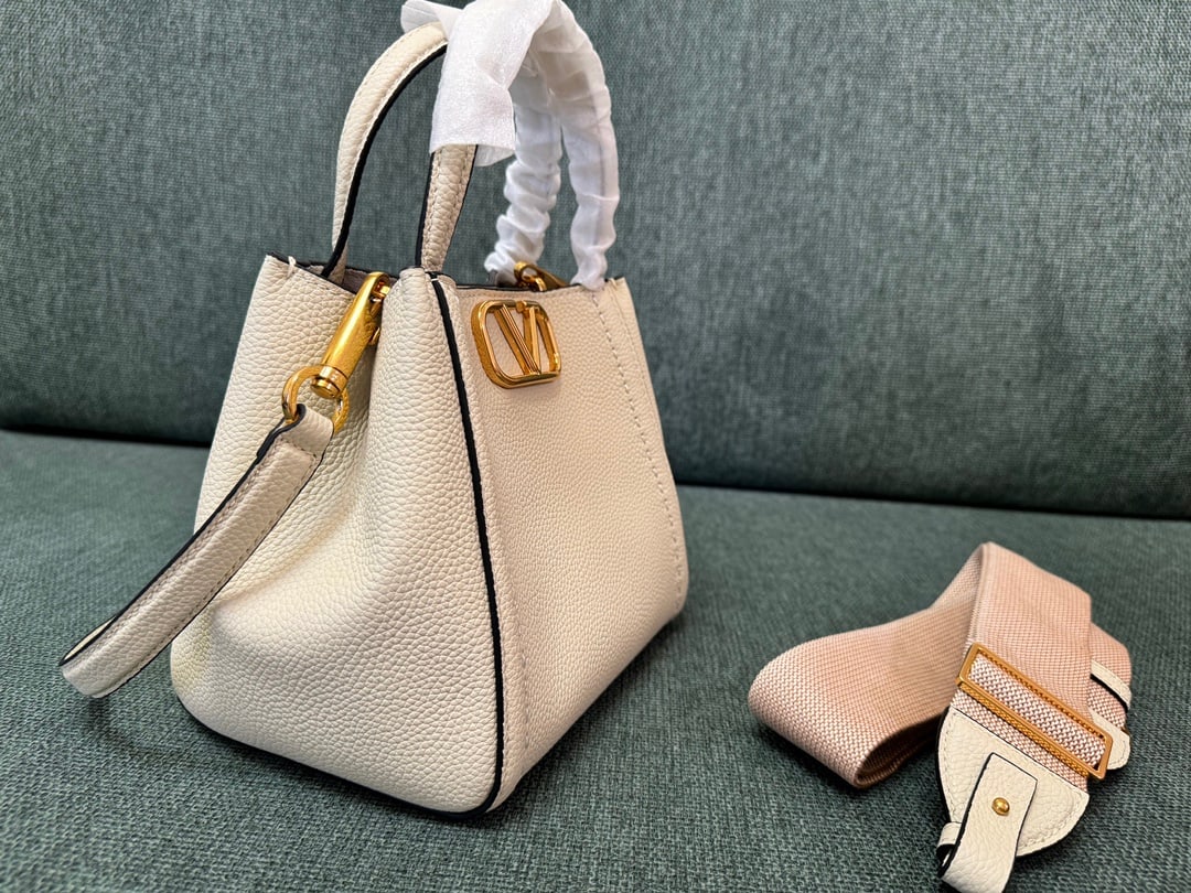 Valentino: Small off-white VALENTINO small grained calfskin handbag with metal VLOGO SIGNATURE element. This handbag can be carried on the shoulder, crossbody, or by hand. Features include vintage brass distress
