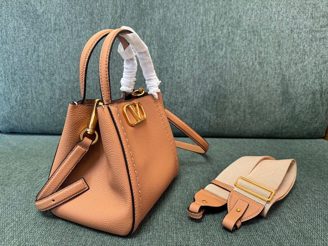 Valentino: Small brown VALENTINO small grained calfskin handbag with metal VLOGO SIGNATURE element. This handbag can be carried on the shoulder, crossbody, or by hand. Features include vintage brass distressed h