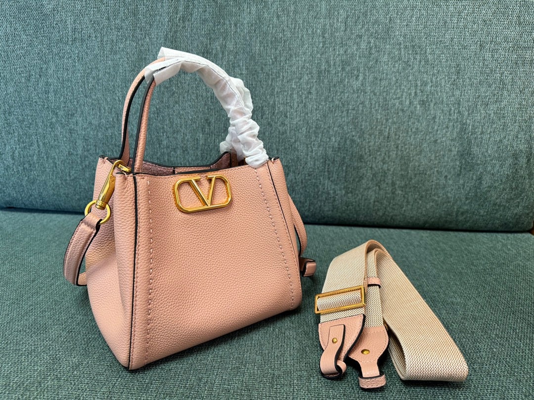 Valentino: Small nude pink VALENTINO small grained calfskin handbag with metal VLOGO SIGNATURE element. This handbag can be carried on the shoulder, crossbody, or by hand. Features include vintage brass distress