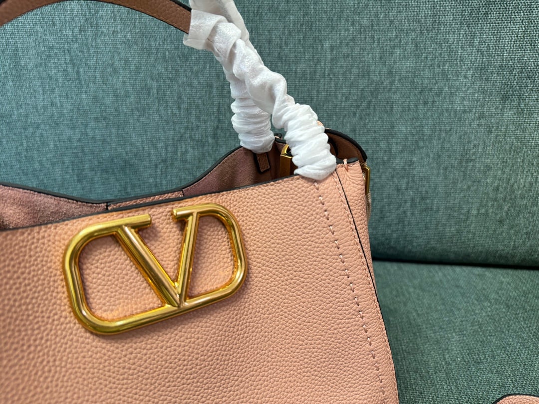 Valentino: Large nude pink VALENTINO small grained calfskin handbag with metal VLOGO SIGNATURE element. This handbag can be carried on the shoulder, crossbody, or by hand. Features include vintage brass distress