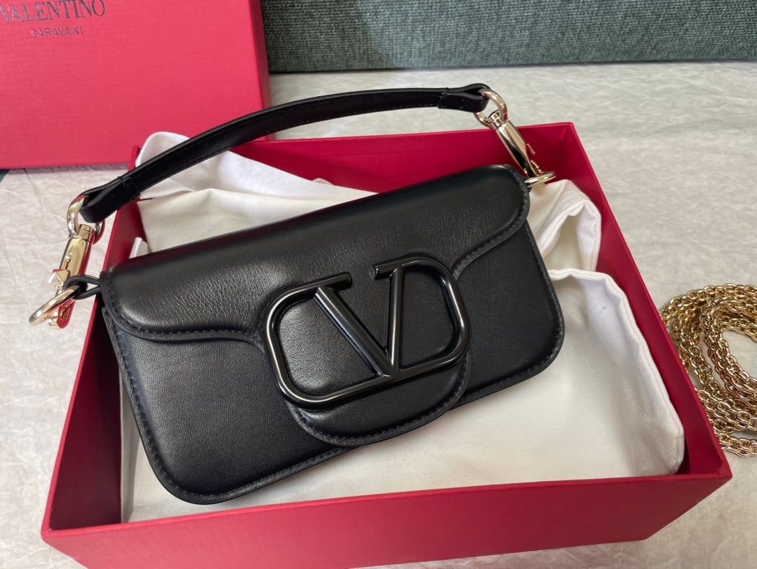 Valentino: Black Valentino calfskin handbag with metal V-logo and Signacar trim - features detachable handles and a detachable sliding chain for shoulder, crossbody, or hand carrying. Vintage brass distressed fi