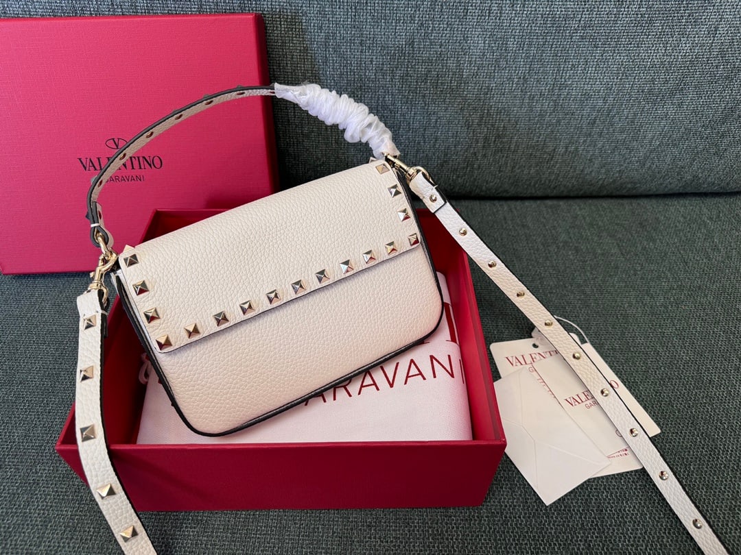Valentino: White Valentino envelope-style small crossbody clutch bag with detachable shoulder strap, magnetic closure, and light gold stud embellishments. Dimensions: 13.5 x 19 x 3 cm. A wonderful gift for you o