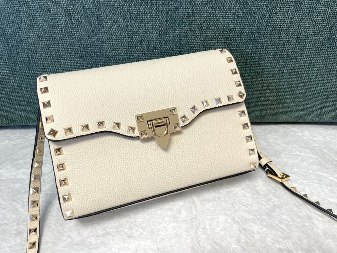 Valentino: White Valentino messenger bag with tumbled gold studs. Simple design, adjustable shoulder strap, and one interior slip pocket. Leather: Plain tumbled cowhide. Size: 22.5 x 5 x 16 cm. A wonderful gift 