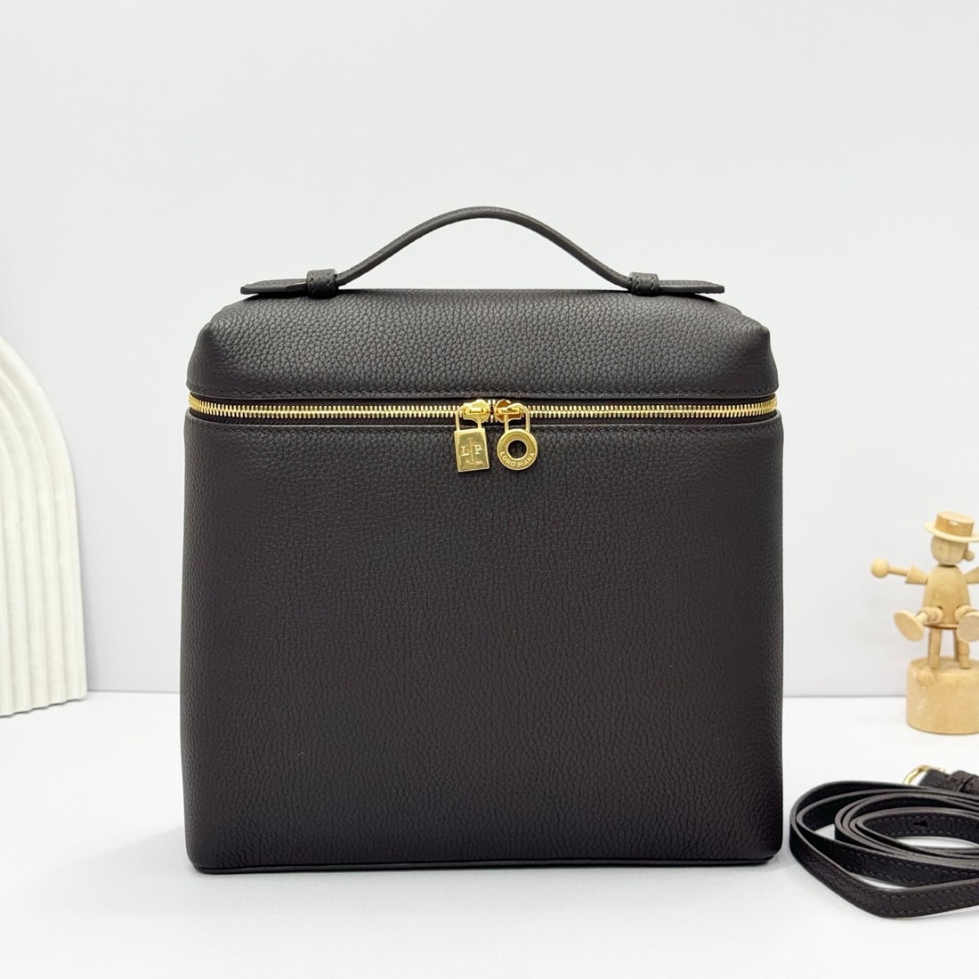 Loropiana Extra Pocket L23.5 Backpack: The Loropiana Extra Pocket L23.5 backpack in coffee color transforms a minimalist design into a large-capacity square bag, elongated towards the base. Crafted from calfskin, the subtle hammered textur