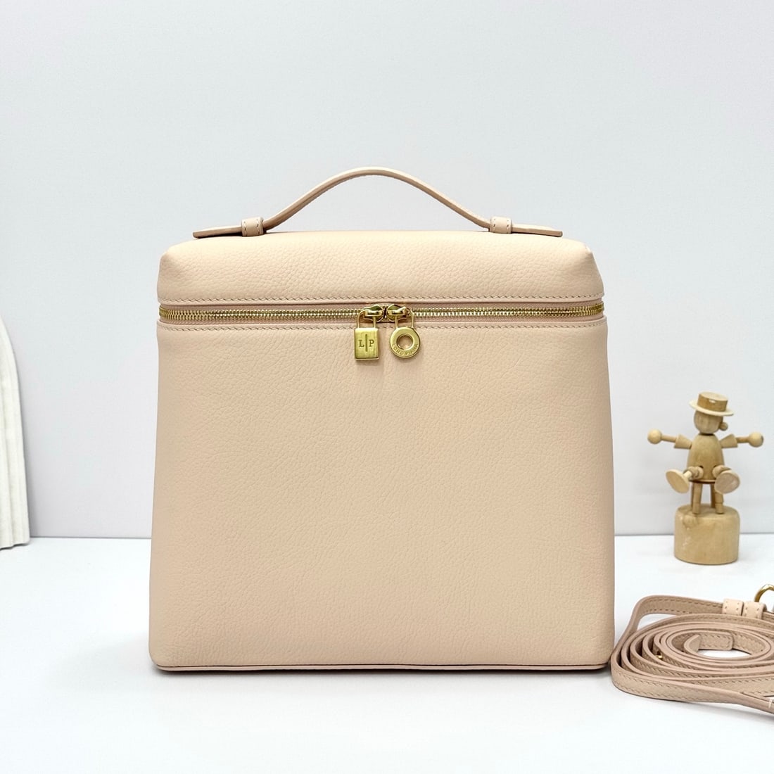 Loropiana Extra Pocket L23.5 Backpack: The Loropiana Extra Pocket L23.5 backpack in creamy honey transforms a minimalist design into a spacious square bag, elongated towards the base. Crafted from calfskin, the subtle hammering enhances th