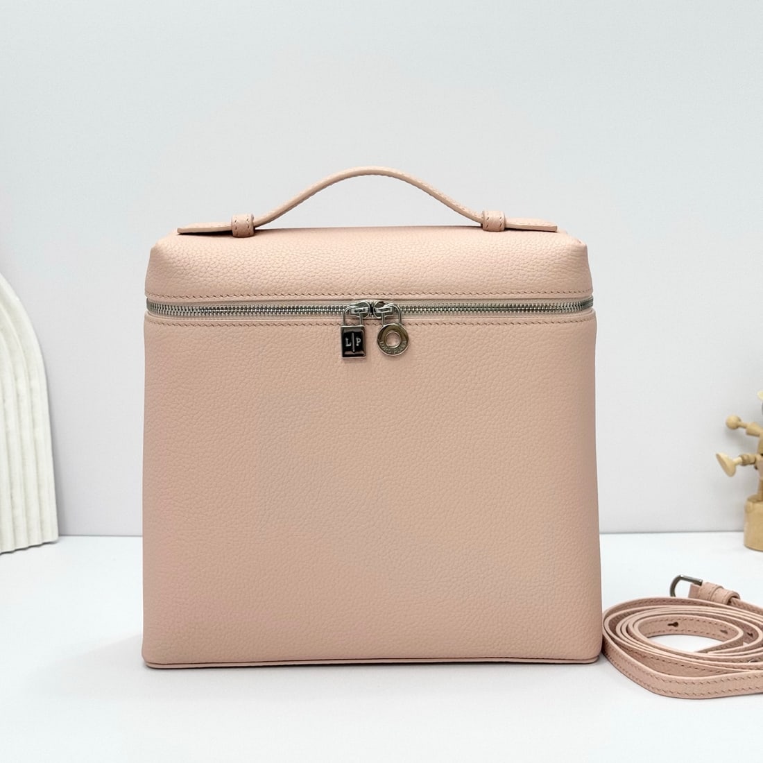 Loropiana Extra Pocket L23.5 Backpack: The Loropiana Extra Pocket L23.5 in Marble Pink transforms a minimalist design into a spacious square bag, elongated towards the base. Crafted from calfskin, the subtle hammering enhances the leather'