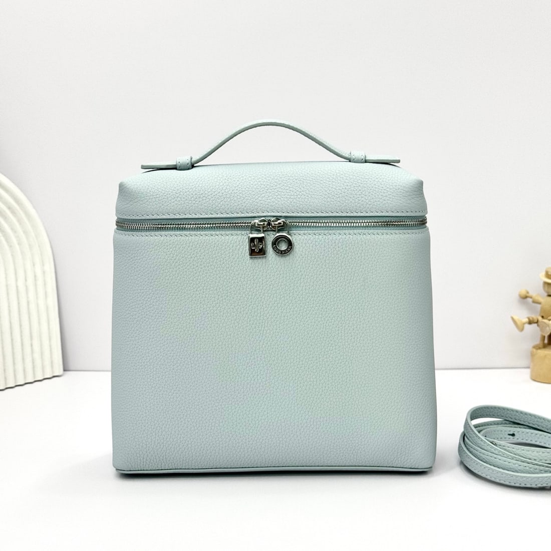 Loropiana Extra Pocket L23.5 Backpack: The Loropiana Extra Pocket L23.5 backpack in light blue transforms a minimalist design into a large-capacity square bag, elongated towards the base. Crafted from calfskin, the subtle hammered texture 
