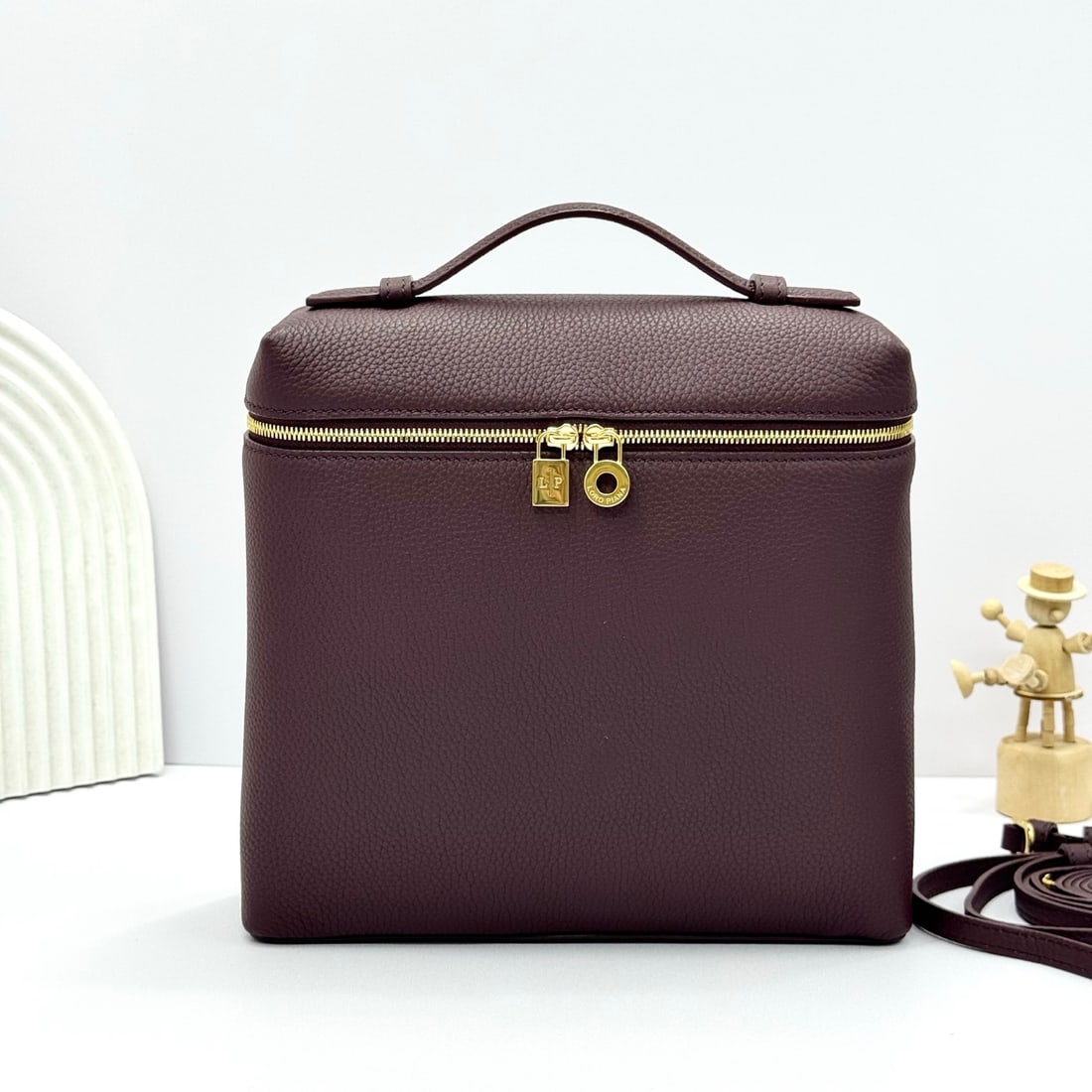 Loropiana Extra Pocket L23.5 Backpack: The Loropiana Extra Pocket L23.5 backpack in a red bean color transforms a minimalist design into a large-capacity square bag, elongated towards the base. Crafted from calfskin, the subtle hammering e