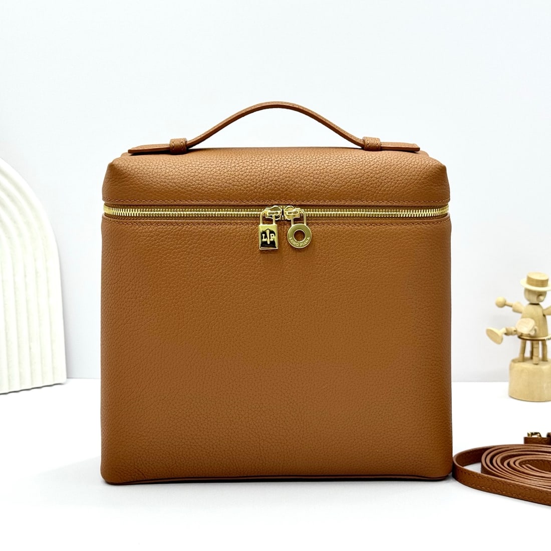 Loropiana Extra Pocket L23.5 Backpack: The Loropiana Extra Pocket L23.5 backpack with a tobacco brown and gold clasp transforms a minimalist design into a large, square bag that elongates towards the base. Crafted from calfskin, the subtle
