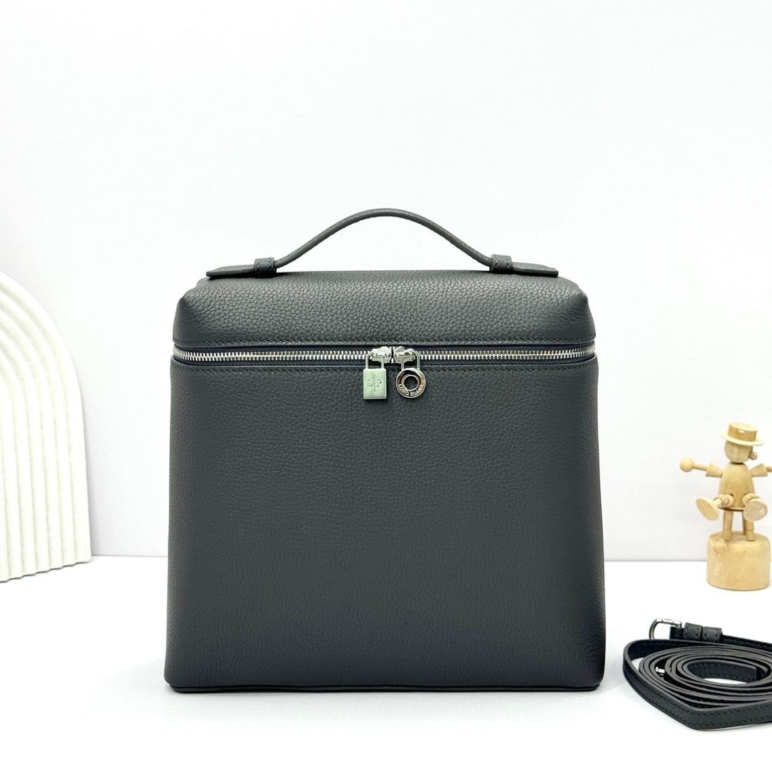 Loropiana Extra Pocket L23.5 Backpack: The Loropiana Extra Pocket L23.5 backpack in dark gray transforms a minimalist design into a large-capacity square bag, elongated towards the base. Crafted from calfskin, the subtle hammering enhances