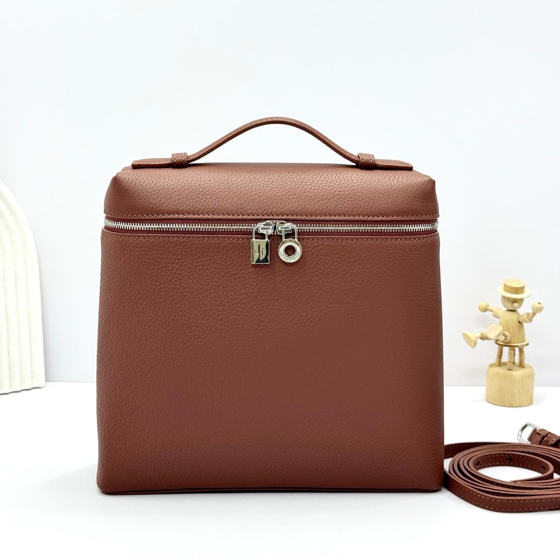 Loropiana Extra Pocket L23.5 Backpack: The Loropiana Extra Pocket L23.5 backpack in brick red transforms a minimalist design into a large-capacity square bag, elongated towards the base. Crafted from calfskin, the subtle hammered texture e