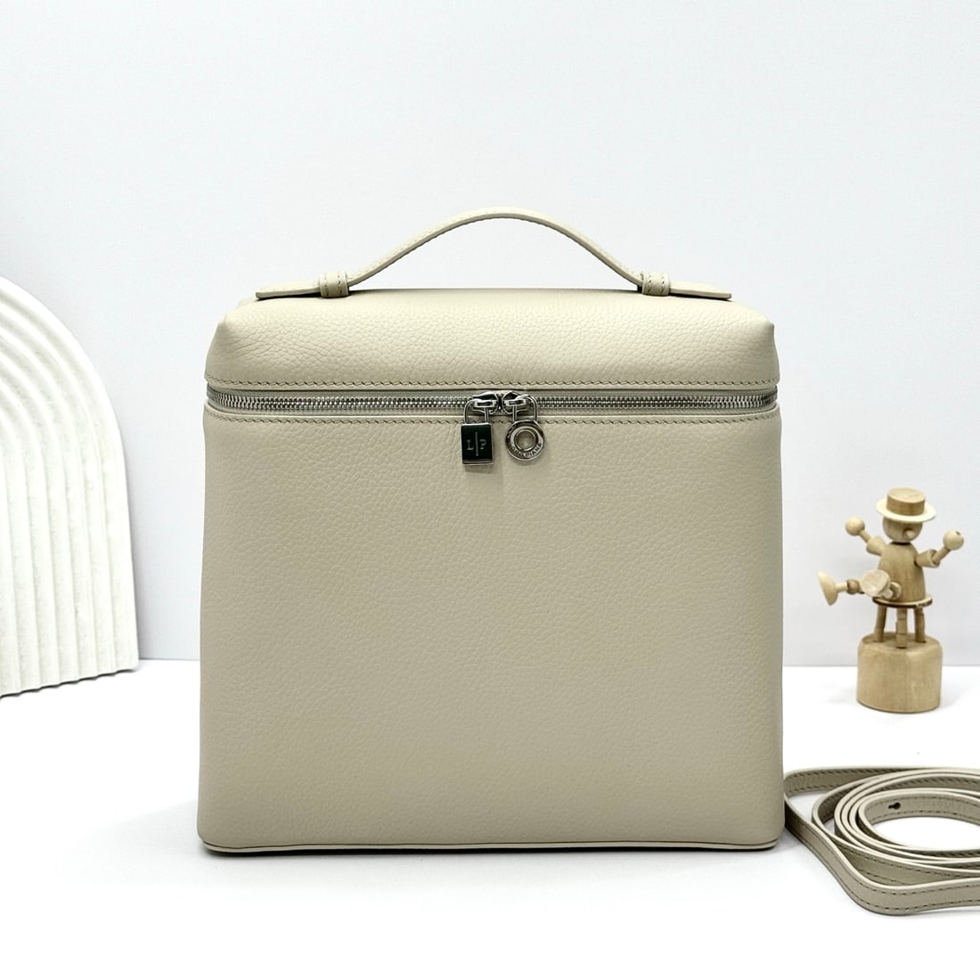 Loropiana Extra Pocket L23.5 Backpack: The Loropiana Extra Pocket L23.5 backpack in light beige transforms a minimalist design into a spacious square bag, elongated towards the base. Crafted from calfskin, the subtle hammered texture enhan