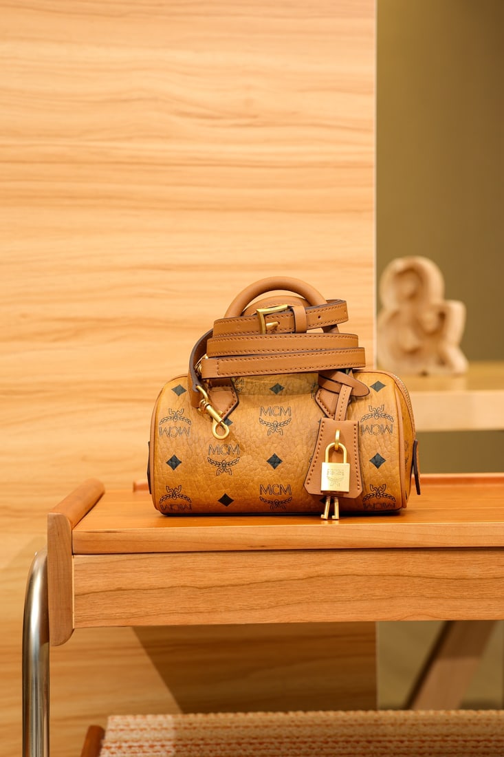 MCM Ella Visetos Cognac Mini Boston Padlock Bag: MCM Ella Visetos Cognac Mini Boston Padlock Bag with All-over Monogram Print. This mini Ella Boston bag features a light pink design and is a high-end travel bag born in Munich's golden age. Its desig