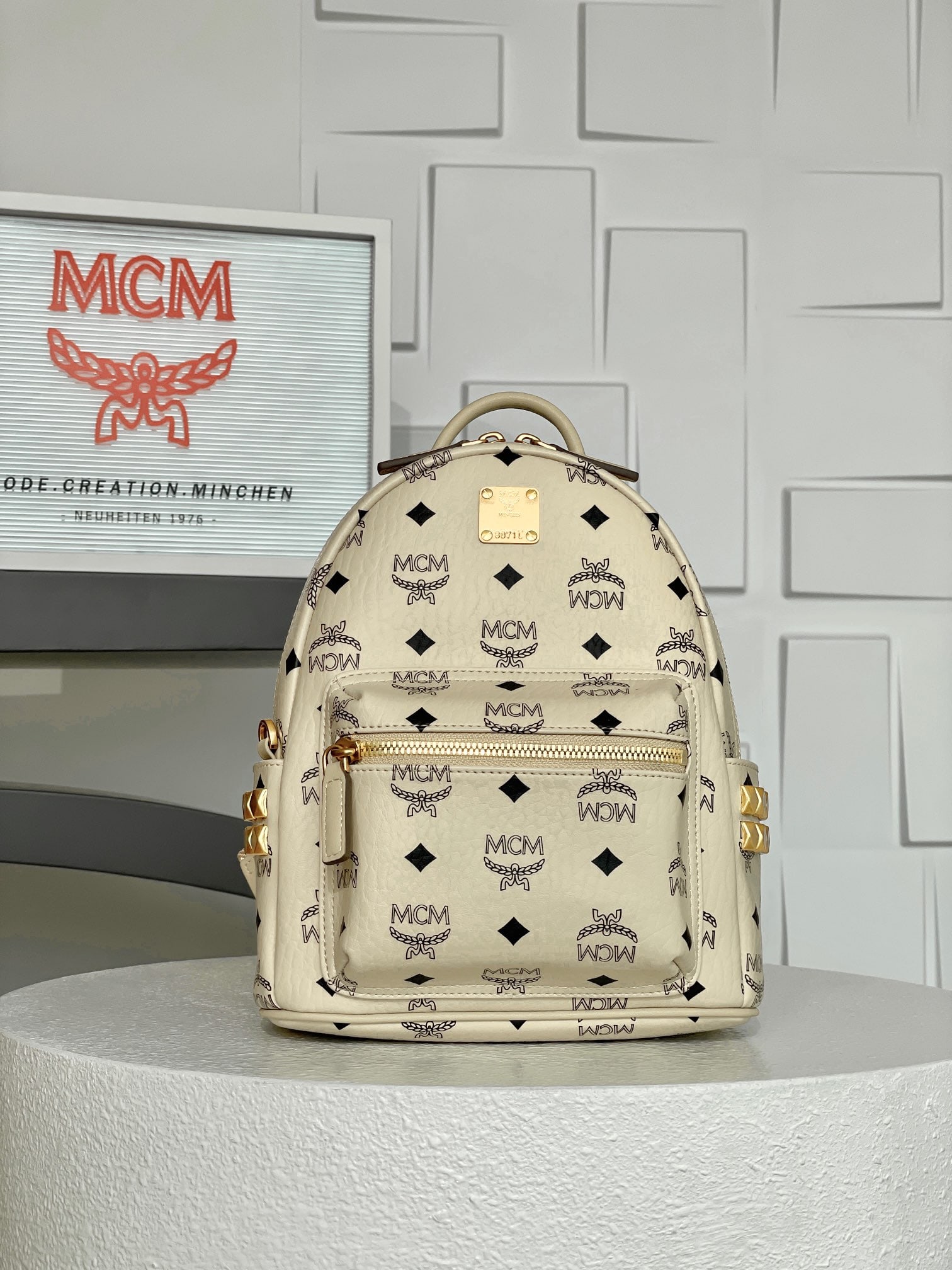 MCM Strak Visetos Off-white Mini Studded Backpack: MCM Strak Visetos Beige Mini Studded Backpack - New Arrival! This new colorway backpack features a well-structured design that redefines the retro feel of hardware. The distressed gold-plated brushed 