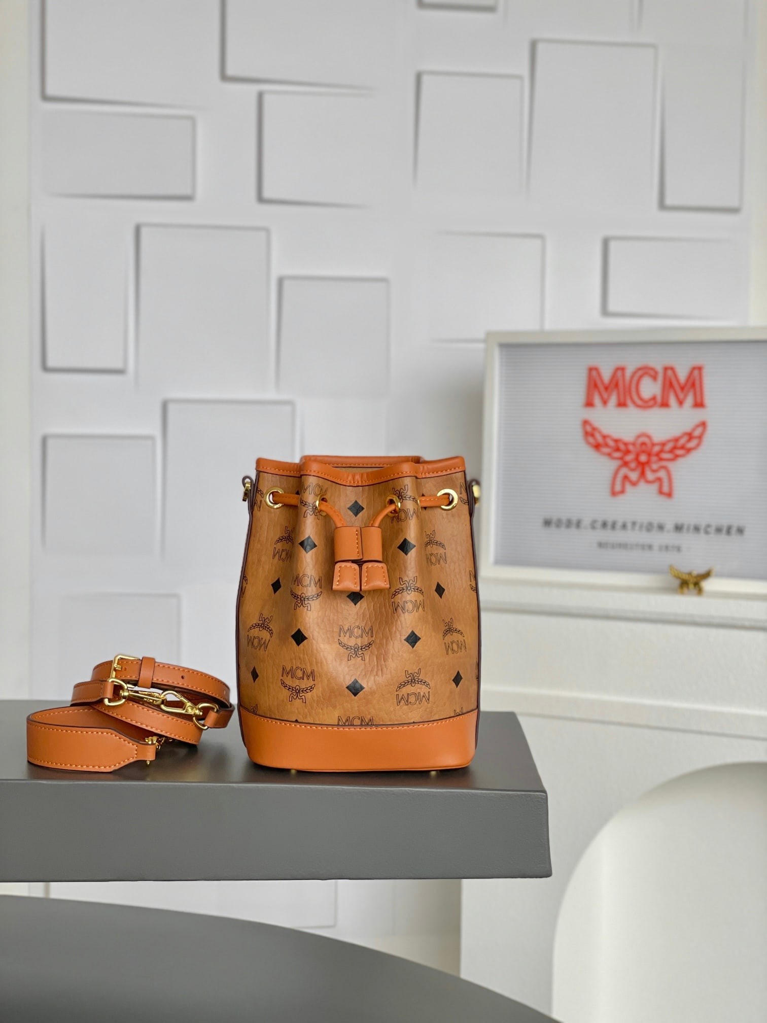 MCM DESSAU VISETOS Mini Drawstring Bucket Bag: MCM DESSAU VISETOS Mini Drawstring Bucket Bag in Classic Cognac. Named after a historically significant center of Bauhaus design, this Dessau drawstring bag pays homage to the renowned art movement wi