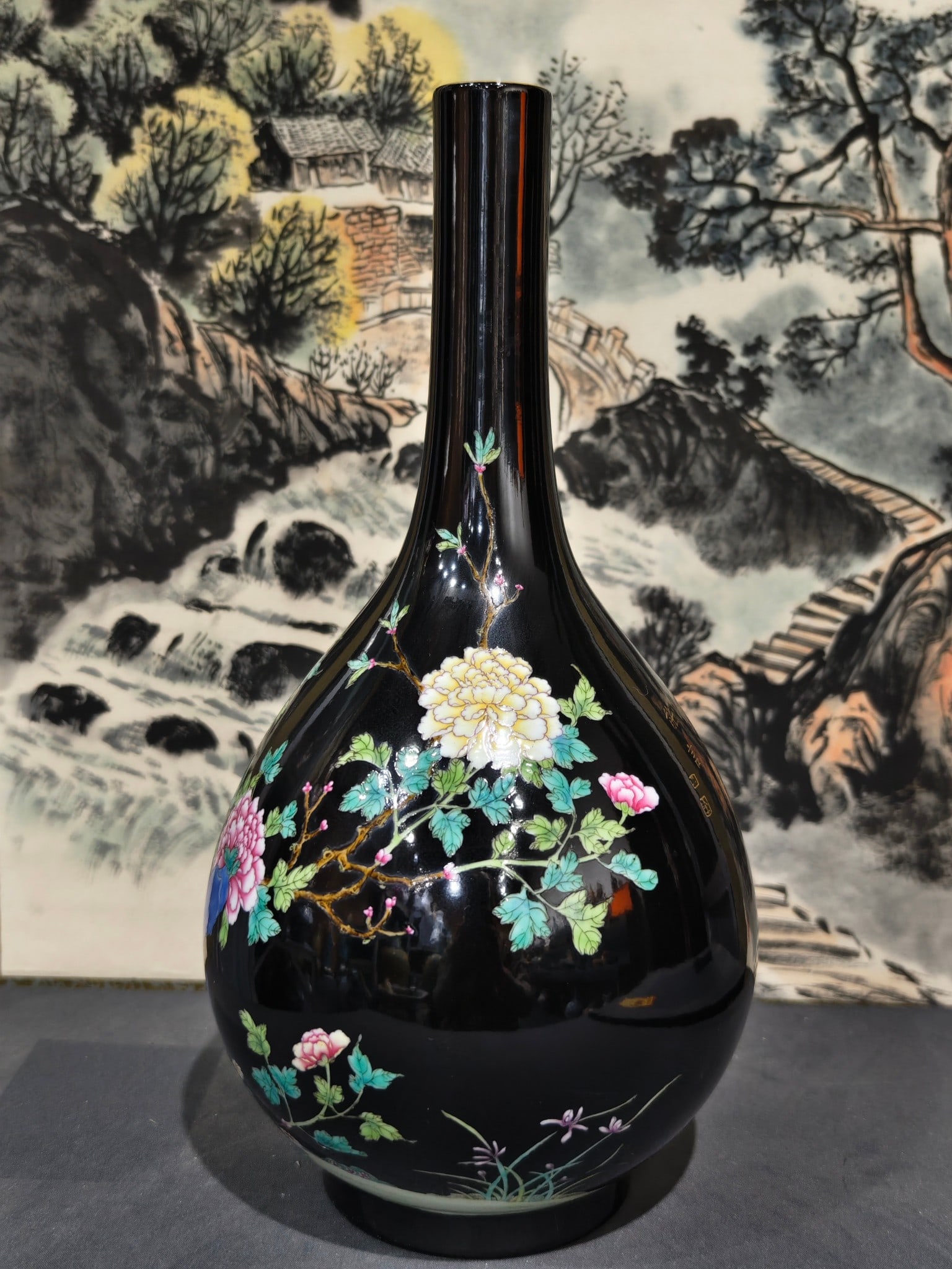 A long-necked duster vase with black ground enamel decoration and gilt decoration of rocks and: A long-necked vase with a black ground enamel decoration and gilt decoration of rocks and flowers, bearing the mark "Made in the Yongzheng Reign of the Great Qing Dynasty," measuring 34 cm in height a