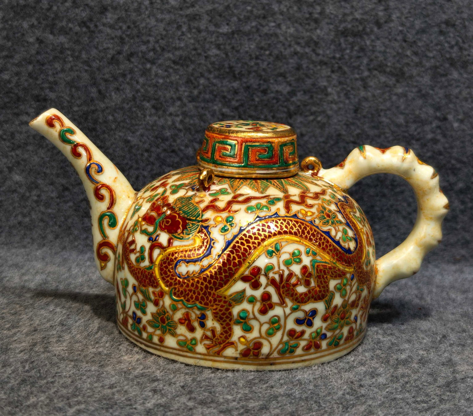 red and green enamel ewer with a dragon and floral design, bearing the mark "Made in the Xuande: A red and green enamel ewer with a dragon and floral design, formerly in the collection and marked "Made in the Xuande period of the Ming Dynasty," measuring 11 cm in height and 21 cm in width. Proven