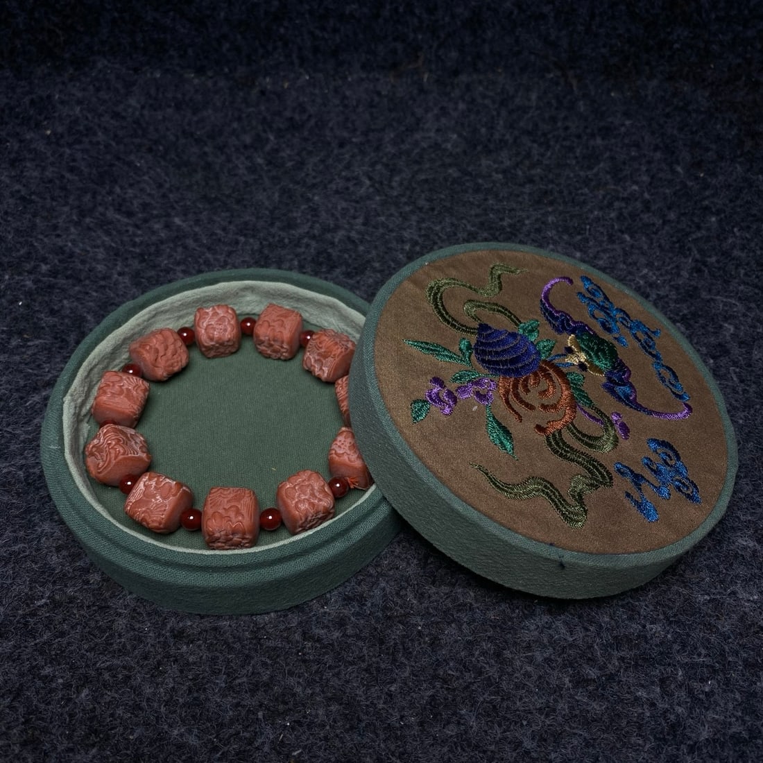 A precious Southern Red Agate bracelet is housed in a fine embroidered box used by the imperial: This is a finely embroidered box used by the imperial court, containing a precious Southern Red Agate bracelet. The bracelet's dimensions are: diameter 15mm. The box's dimensions are: diameter 12cm, h