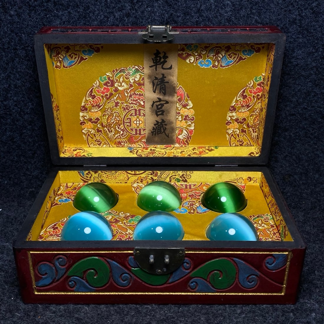 A cat's-eye stone handball is treasured inside a lacquerware collection box made by the Qianlong: A Qing Dynasty Qianlong Emperor's Imperial Carved Lacquerware Collection Box Contains a Cat's Eye Stone Handball. Handball dimensions: Diameter 50mm. Lacquerware box dimensions: Length/Width/Height 25