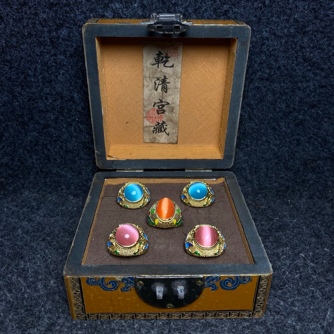 A cloisonne ring inlaid with cat's eye stones, treasured inside a lacquerware box made by Emperor: A cloisonne enamel ring inlaid with a cat's eye stone, made by the Qianlong Emperor of the Qing Dynasty. Lacquer box dimensions: 13/13/7cm (L/W/H). Provenance:Private collection from a professor in Un
