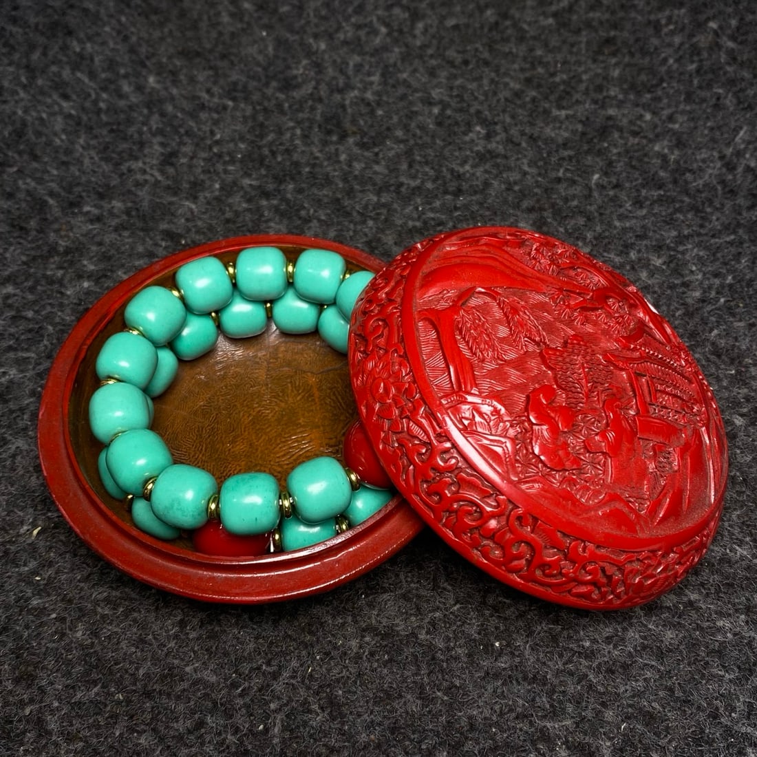 A turquoise bracelet is treasured inside a carved red lacquerware box.: A turquoise bracelet engraved in a carved lacquerware box, containing precious artifacts. Bracelet dimensions: diameter 14mm. Box dimensions: diameter 10.2cm, height 6cm. Provenance:Private collection