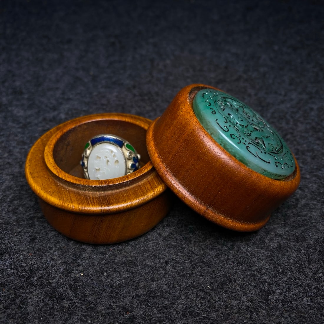 A cloisonn?? openwork ring inlaid with Hetian jade, treasured within a rosewood jewelry box inlaid: rosewood jewelry box inlaid with jade contains a cloisonn?? enamel ring inlaid with Hetian jade. The box measures 6.5cm in diameter and 5.3cm in height. Provenance:Private collection, Liverpool, The U