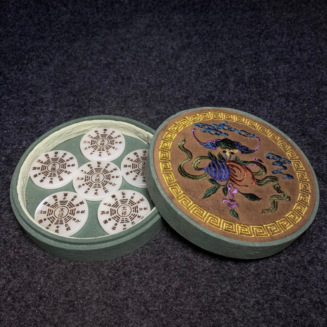 The exquisite embroidered box contains a precious ancient jade bi pendant.: The exquisite embroidered box contains a precious ancient jade bi (disc) pendant. The bi's dimensions are: diameter 4.8cm. The jewelry box's dimensions are: diameter 16cm, height 4.5cm. Provenance:Pri