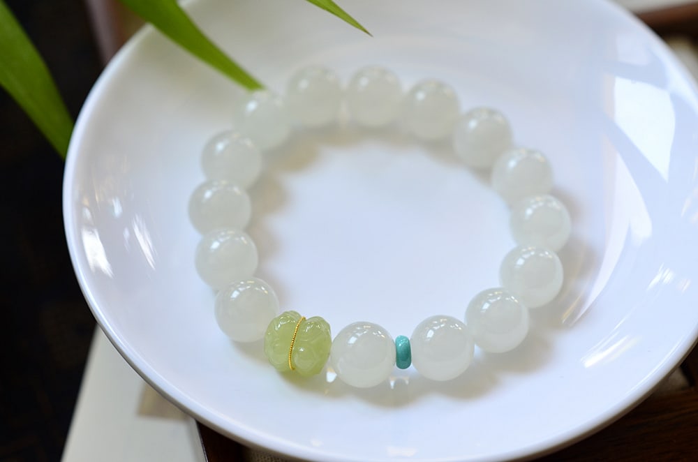 Natural Hetian white jade bracelet: (Agarwood and White Jade, Fragrant with Time) Approximately 12 pieces of natural Hetian white jade, inlaid with Hetian jade twin lotus flowers in 18k gold, and raw turquoise. Provenance:Private collec