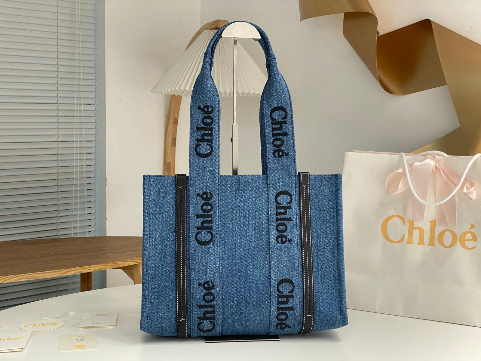 Chloe Woody: We offer FREE SHIPPING for both domestic and international clients who bid over $500. The Chloe Woody denim blue tote bag features the iconic Chloe logo embroidered on a denim blue ribbon, giving it a