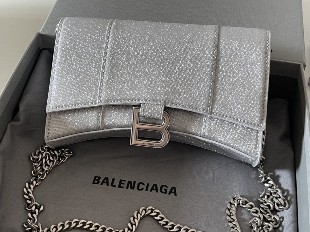 Balenciaga: We offer FREE SHIPPING for both domestic and international clients who bid over $500. The silver Balenciaga hourglass bag with chain strap features a unique and iconic curved shape that is instantly r