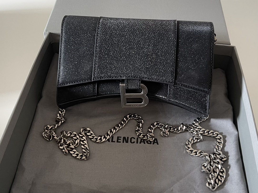 Balenciaga: We offer FREE SHIPPING for both domestic and international clients who bid over $500. This Balenciaga hourglass bag with chain strap in shimmering black features a unique, iconic curved shape that is 