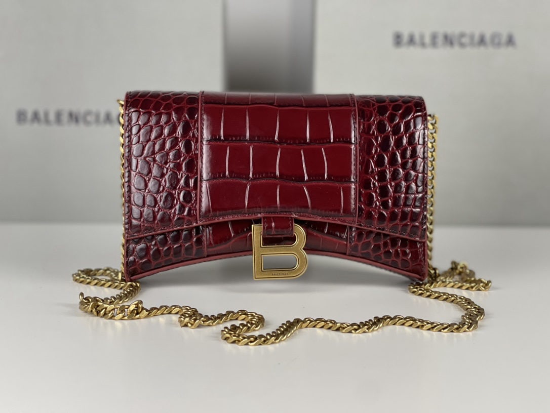 Balenciaga: We offer FREE SHIPPING for both domestic and international clients who bid over $500. This Balenciaga hourglass bag with a crocodile-embossed burgundy design and gold hardware features a unique, iconi