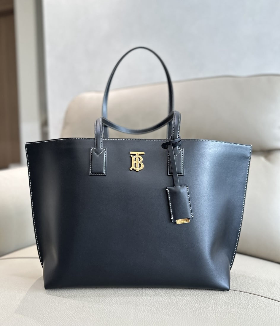 Burberry: We offer FREE SHIPPING for both domestic and international clients who bid over $500. This Burberry tote bag is crafted from select Italian-tanned, top-stitched leather. It features a glossy Thomas Bu