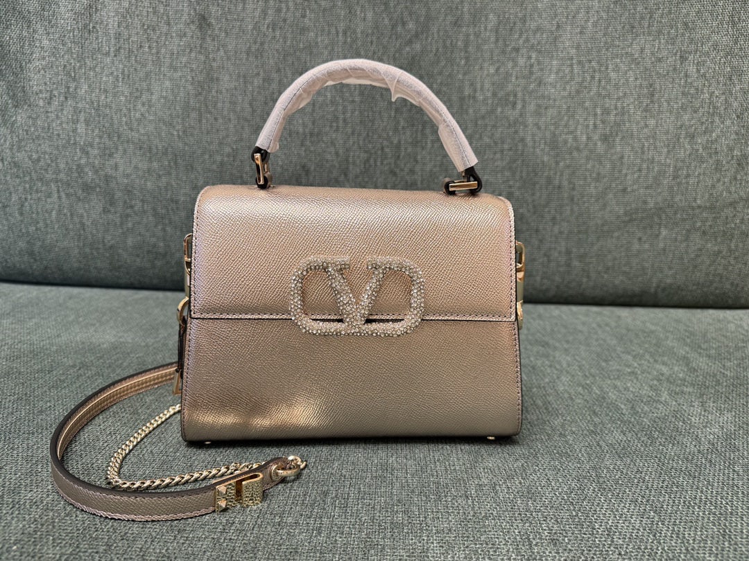 Valentino Garavani VSLING: We offer FREE SHIPPING for both domestic and international clients who bid over $500. The champagne gold and diamond-encrusted mini Valentino Garavani VSLING features an extendable two-tone shoulder s